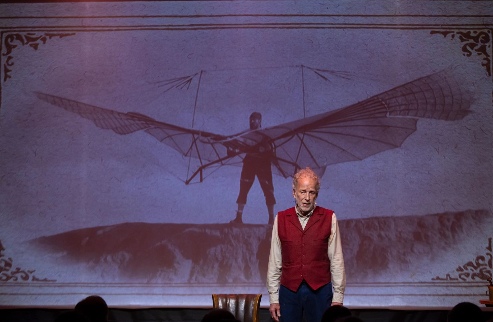Robert Leddy performing before a projected image of early flight