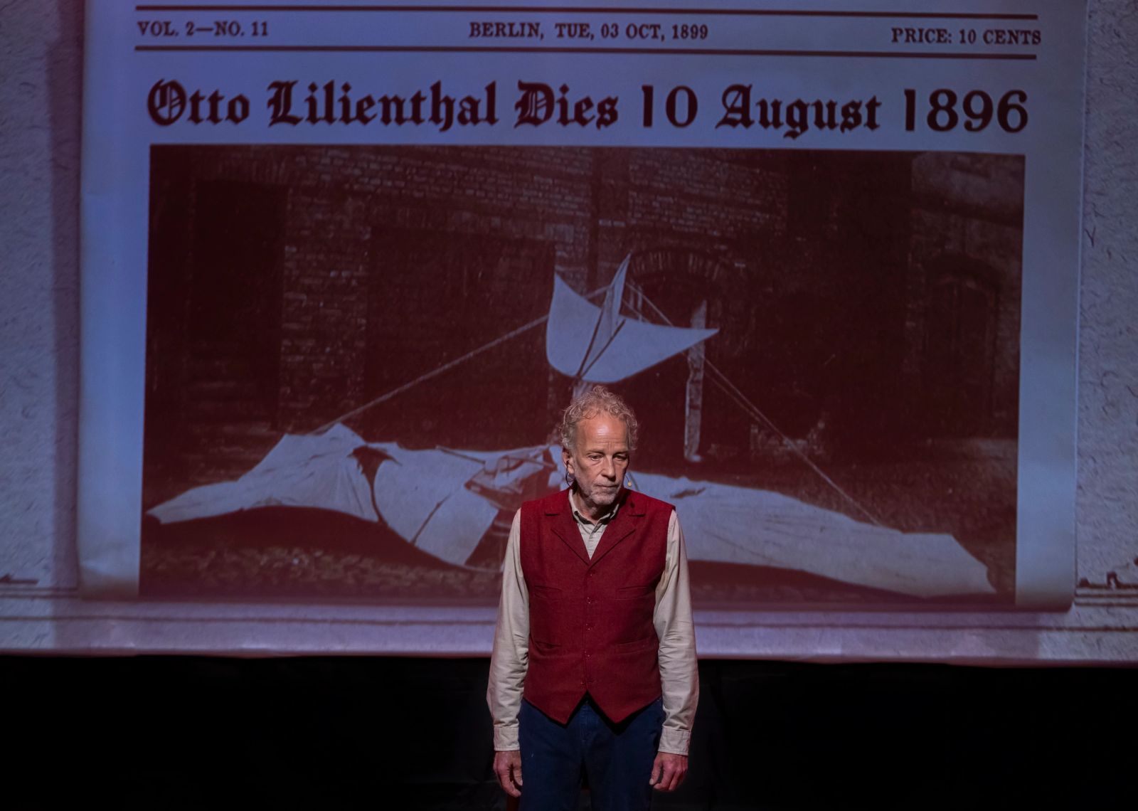 Robert Leddy performing beneath a projected historic newspaper